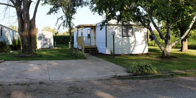 a view of a white house with a large tree