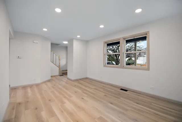 a view of an empty room with window and wooden floor