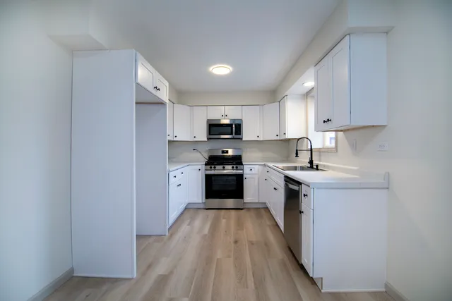 a kitchen with granite countertop a stove top oven a sink dishwasher and a refrigerator with wooden floor