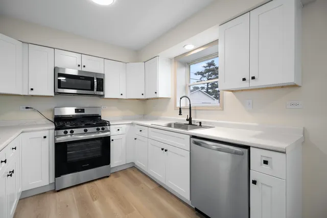 a kitchen with granite countertop white cabinets and stainless steel appliances