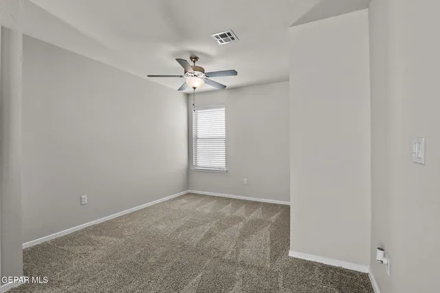 an empty room with a window and ceiling fan