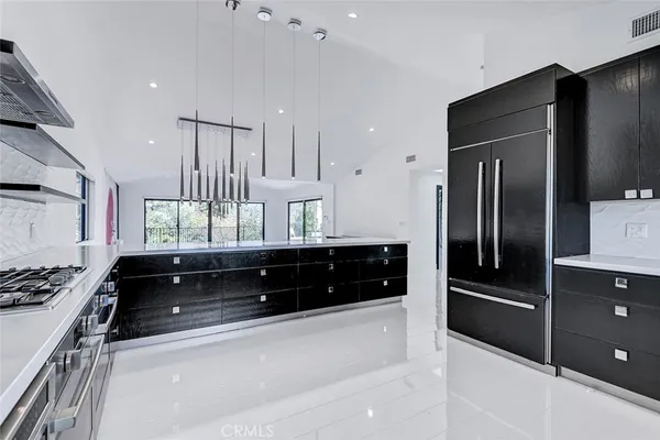 a large kitchen with stainless steel appliances a stove a refrigerator and a sink