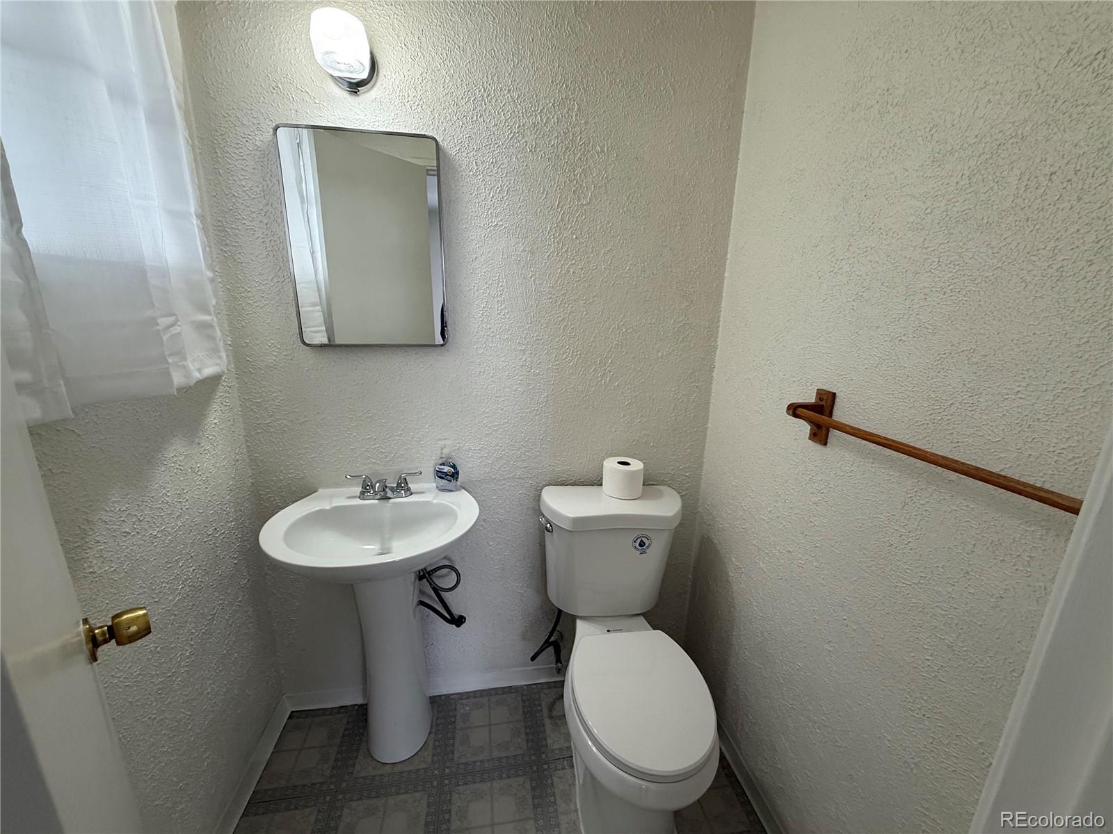 756 Vaughn Street Aurora, CO 80011 - Photo 9 of 22 a bathroom with a toilet a sink and mirror