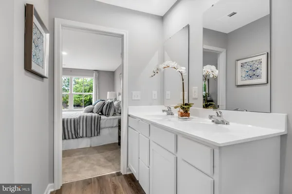 a en suite bathroom with a double vanity sink a mirror and next to a window