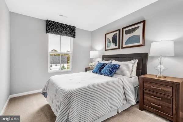 a bedroom with a bed and a lamp on dresser