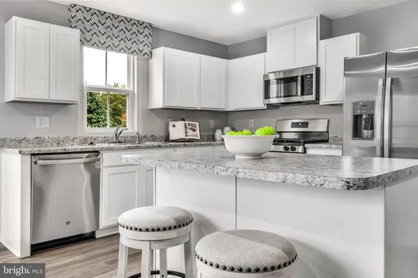 a kitchen with stainless steel appliances granite countertop a sink a stove a microwave a refrigerator and cabinets