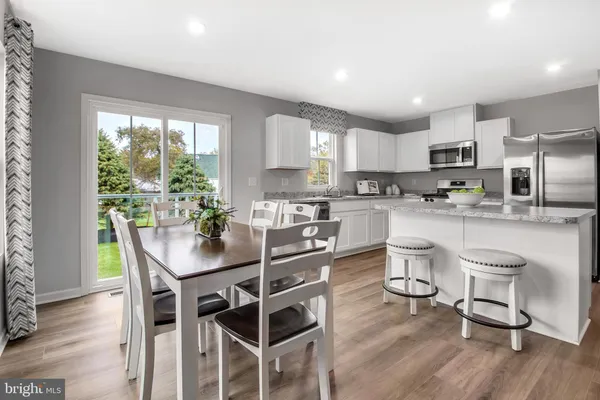 a kitchen with granite countertop stainless steel appliances a dining table chairs and wooden floor