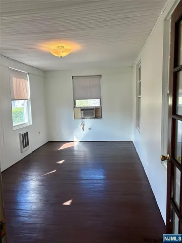 an empty room with wooden floor a fireplace and windows