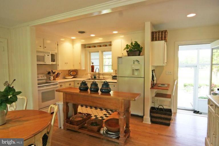 6857 Edge Creek Road St. Michaels, MD 21663 - Photo 6 of 13 a kitchen with stainless steel appliances granite countertop a refrigerator a stove and a dining table with wooden floor