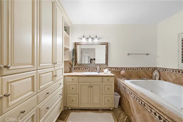 a bathroom with a granite countertop double vanity sink a mirror and a bathtub