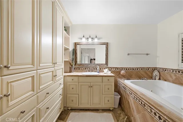 a bathroom with a granite countertop double vanity sink a mirror and a bathtub