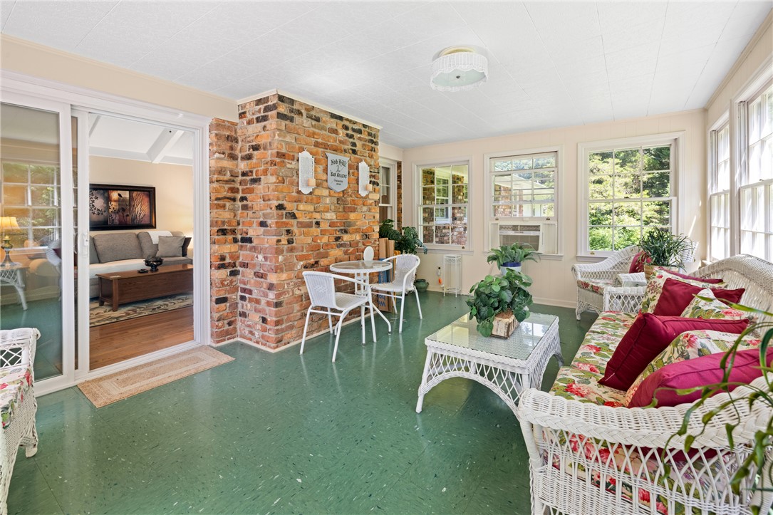 706 Pinewood Drive Pendleton, SC 29670 - Photo 16 of 35 A well-lit sunroom boasts a charming brick feature wall and green flooring, perfect for relaxation.
