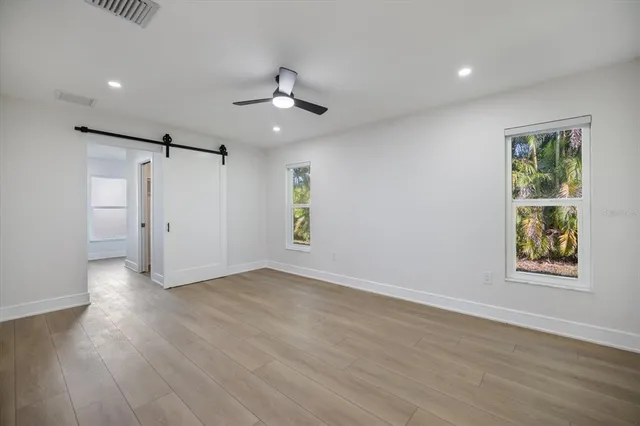 an empty room with wooden floor and a ceiling fan