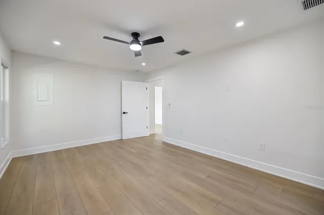 an empty room with wooden floor and windows