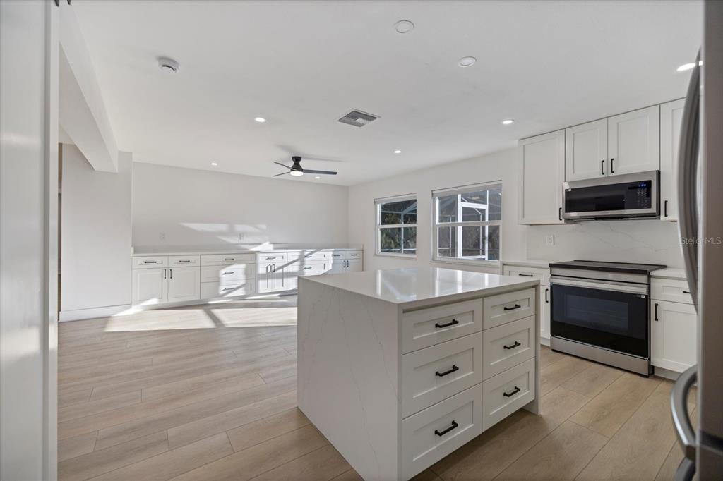 470 Leger Drive Nokomis, FL 34275 - Photo 21 of 51 a kitchen with stainless steel appliances granite countertop a stove top oven a sink dishwasher and a refrigerator with wooden floor
