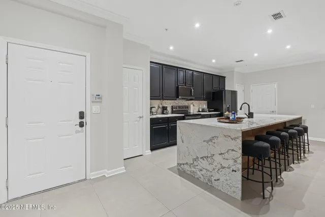a kitchen with stainless steel appliances kitchen island granite countertop a table chairs sink and white cabinets