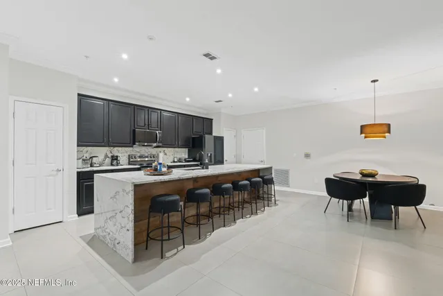 a kitchen with stainless steel appliances granite countertop a table chairs sink refrigerator and cabinets