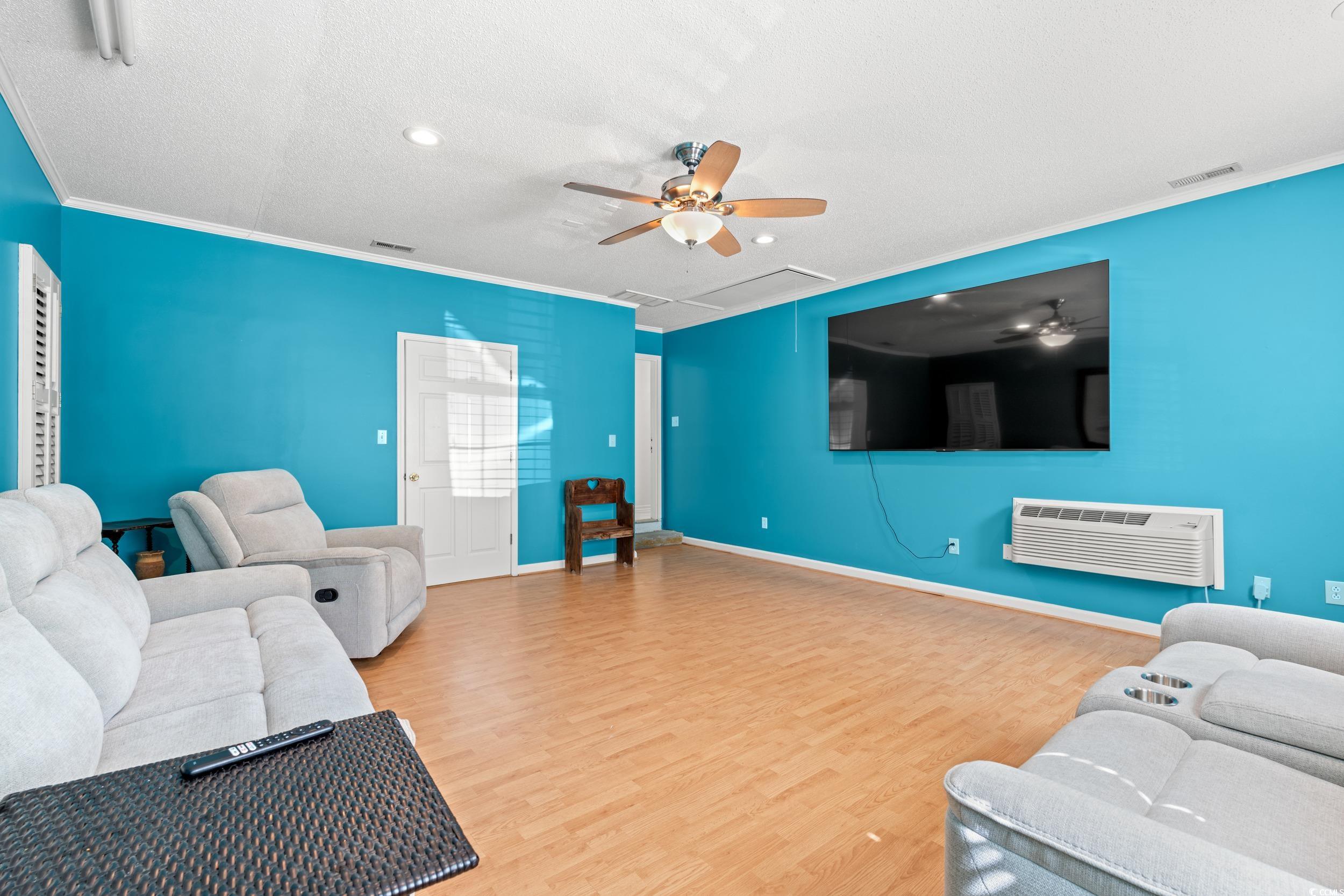 3056 Sweetpine Lane Conway, SC 29527 - Photo 19 of 36 Living area featuring a ceiling fan, ornamental molding, a textured ceiling, wood finished floors, and an AC wall unit