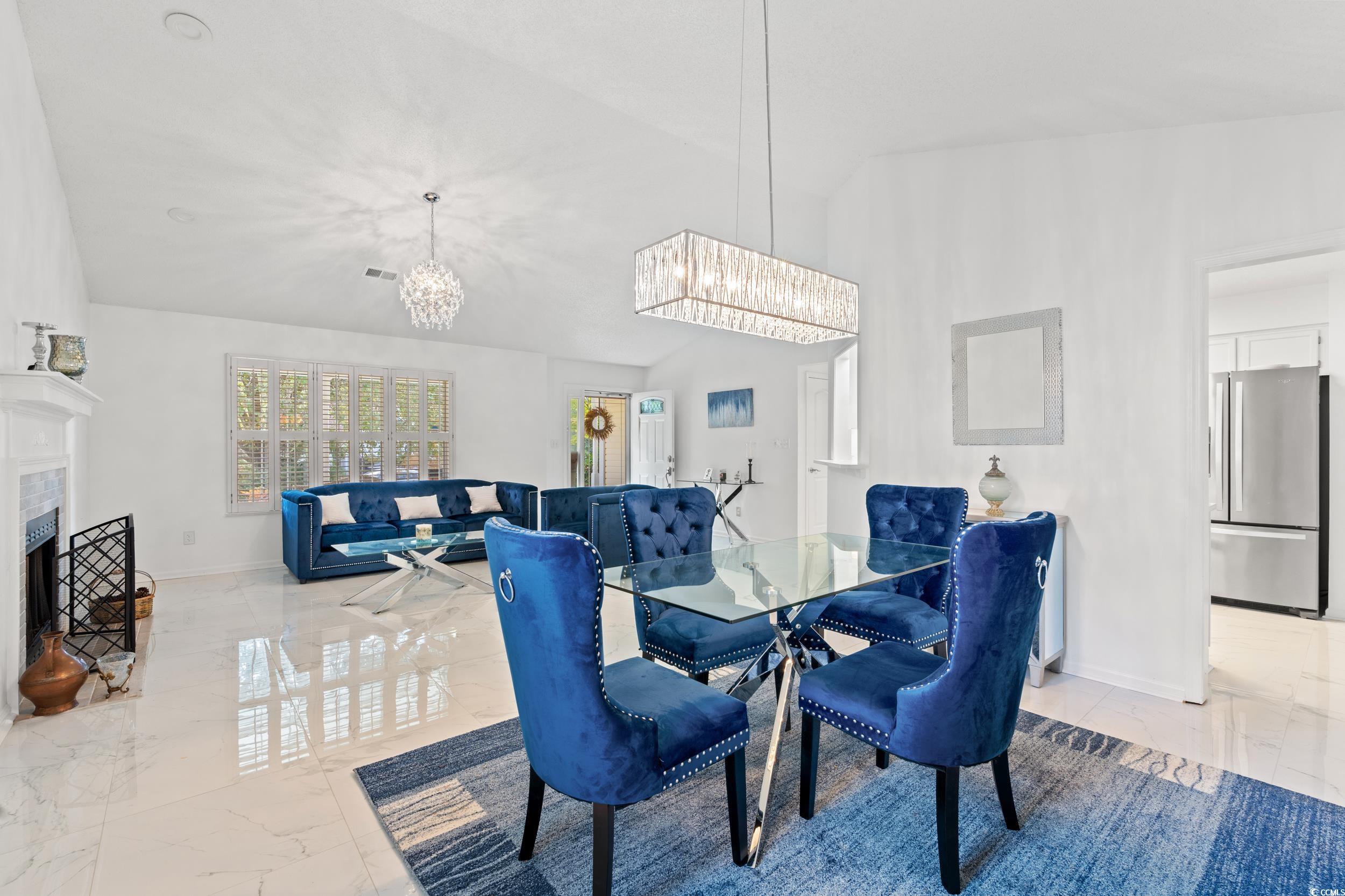 3056 Sweetpine Lane Conway, SC 29527 - Photo 9 of 36 Dining space featuring light marble finish floors, a fireplace, a chandelier, and lofted ceiling