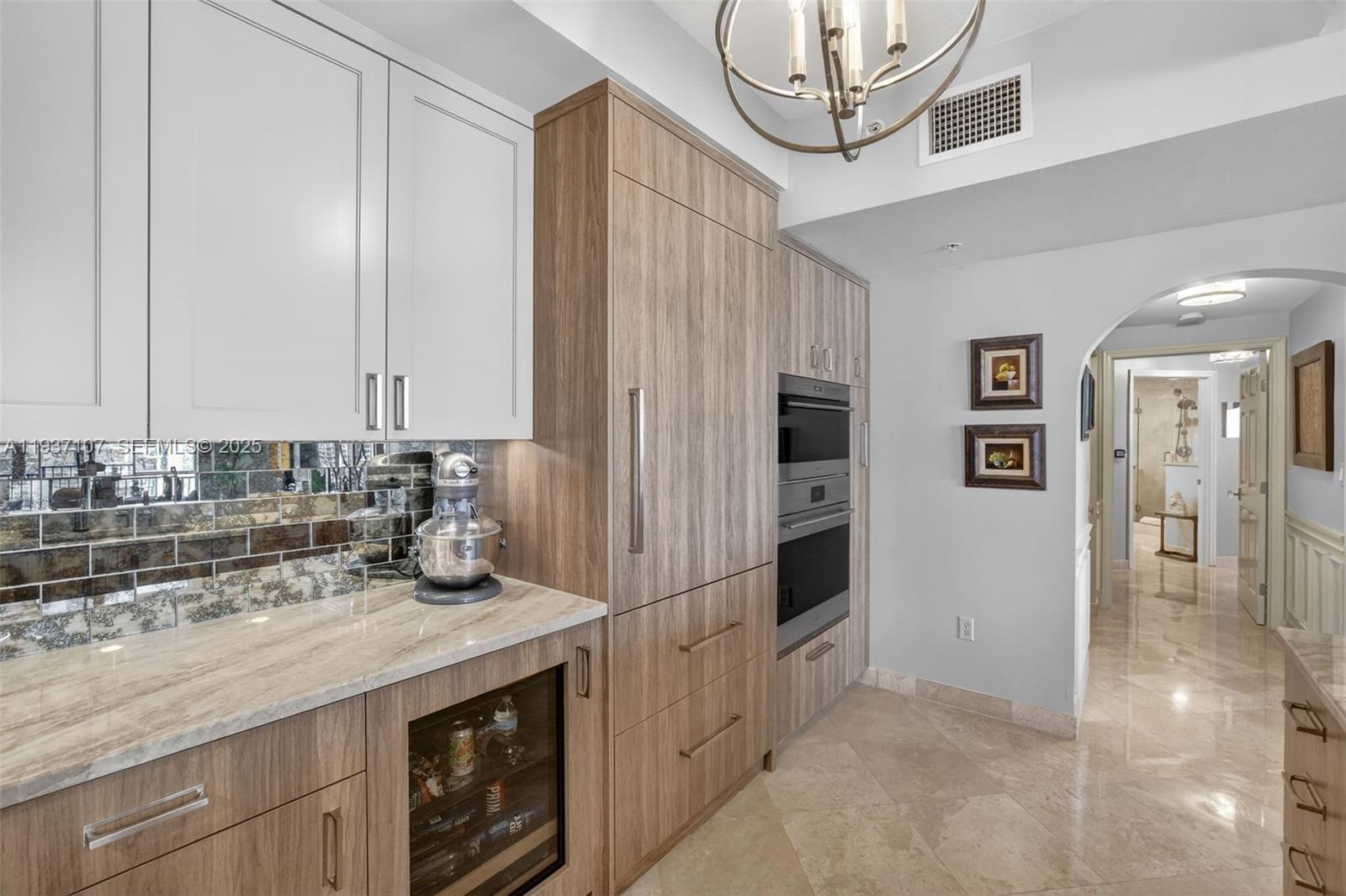 100 South Birch Road, Unit 1103F Fort Lauderdale, FL 33316 - Photo 35 of 80 Spectacular kitchen w/ custom bleached walnut veneer cabinetry by renowned Chicago based millworker. Grain matches from top to bottom. Taj mahal quartzite. Wolf induction cooktop & double oven (w/ microwave / convenction at top oven), Sub Zero Refrigerator & Beverage Cooler, Miele Dishwasher. Sink w/ touchless Brizo faucet, including water filtration faucet. Antiqued mirror backsplash. Wide hallway to bedrooms, bathrooms and laundry room. through archway