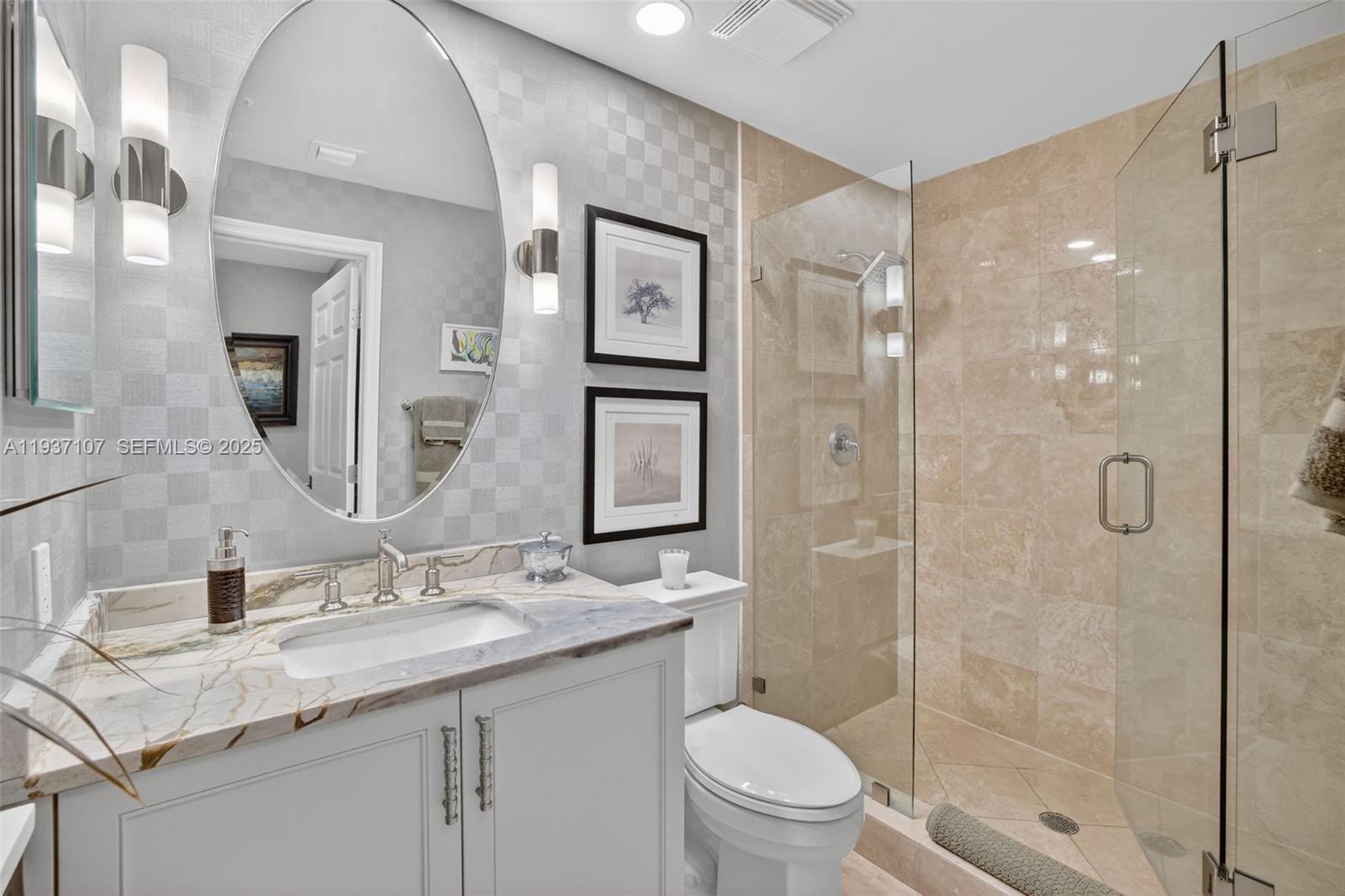 100 South Birch Road, Unit 1103F Fort Lauderdale, FL 33316 - Photo 49 of 80 Guest bathroom w/ designer wall coverings, sconces, wall hung mirror. Custom wood vanity. Marble shower walls and vanity counter, Kohler toilet and frameless shower doors