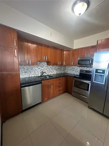 a kitchen with stainless steel appliances granite countertop a stove a sink and a refrigerator