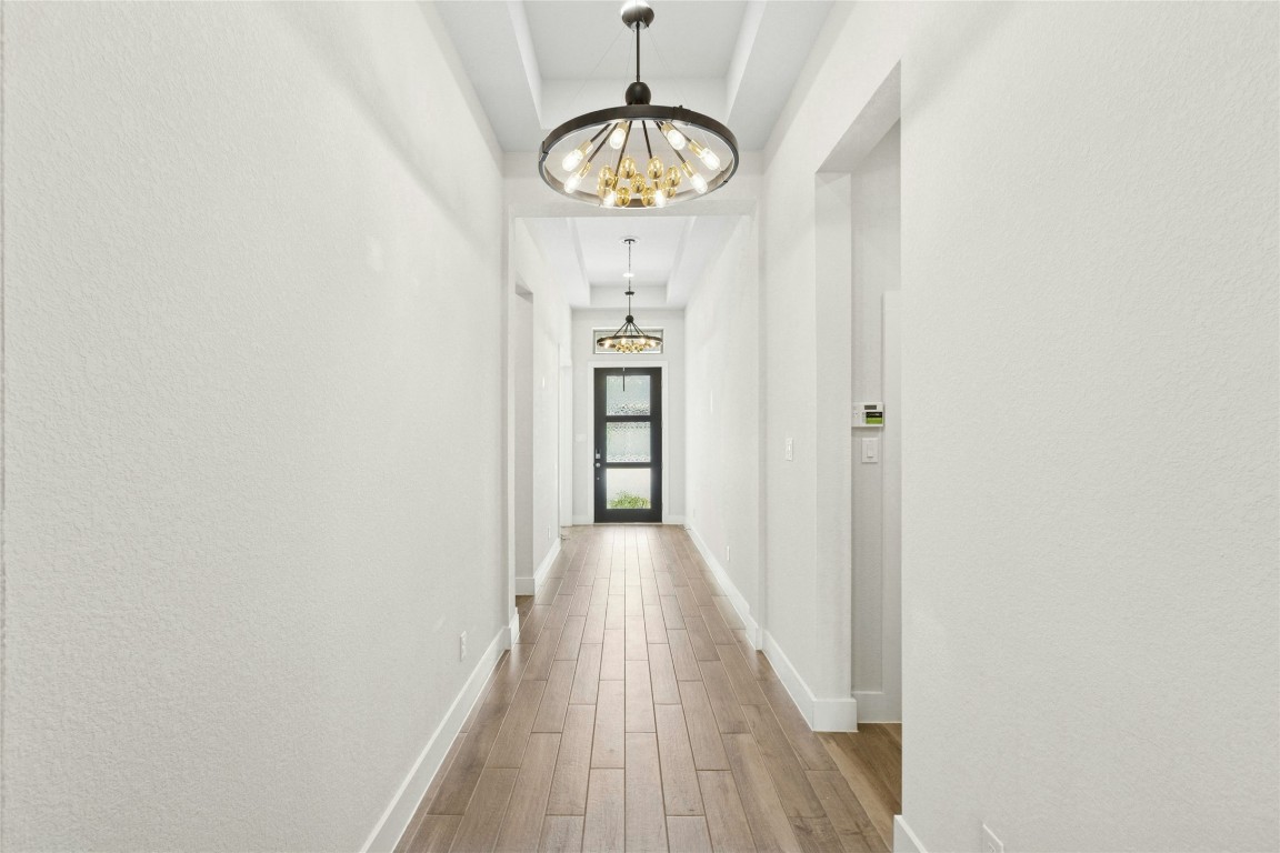 1121 Spring Gulch Lane Georgetown, TX 78628 - Photo 4 of 33 a view of a hallway with wooden floor and a chandelier