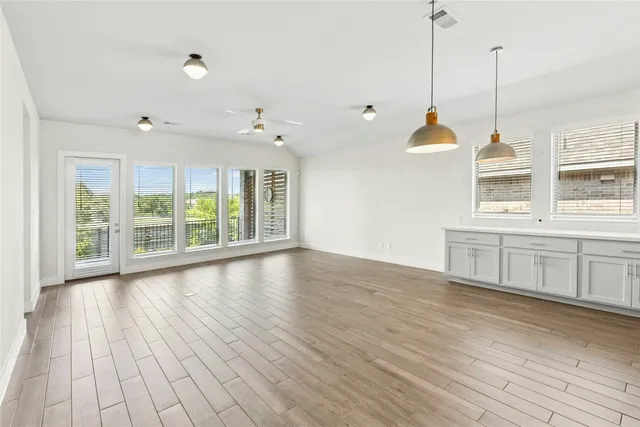 a view of an empty room with a window and wooden floor