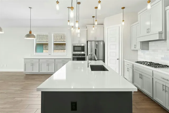 a kitchen with stainless steel appliances kitchen island granite countertop a stove a sink and a refrigerator