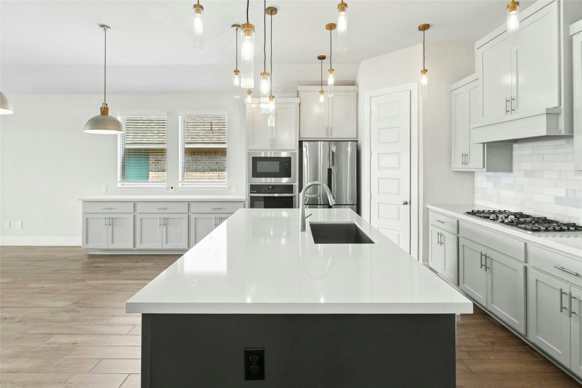 1121 Spring Gulch Lane Georgetown, TX 78628 - Photo 7 of 33 a kitchen with stainless steel appliances kitchen island granite countertop a stove a sink and a refrigerator