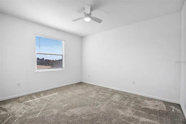 an empty room with a window and ceiling fan