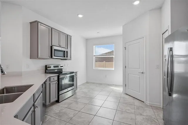 a kitchen with granite countertop a stove a sink and a refrigerator