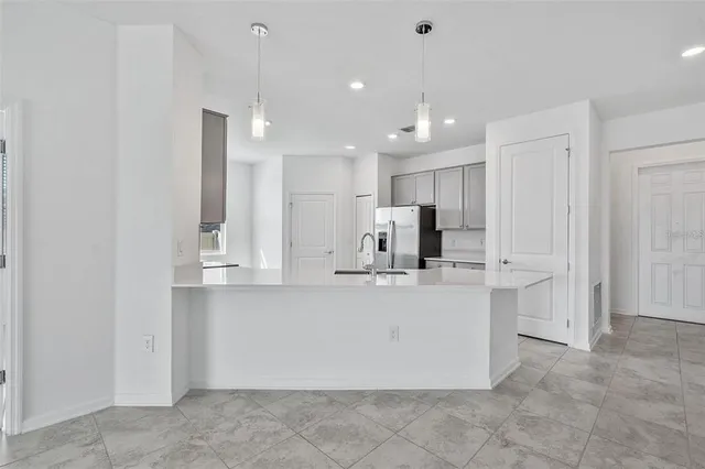 a large kitchen with kitchen island a sink a center island stainless steel appliances and a refrigerator