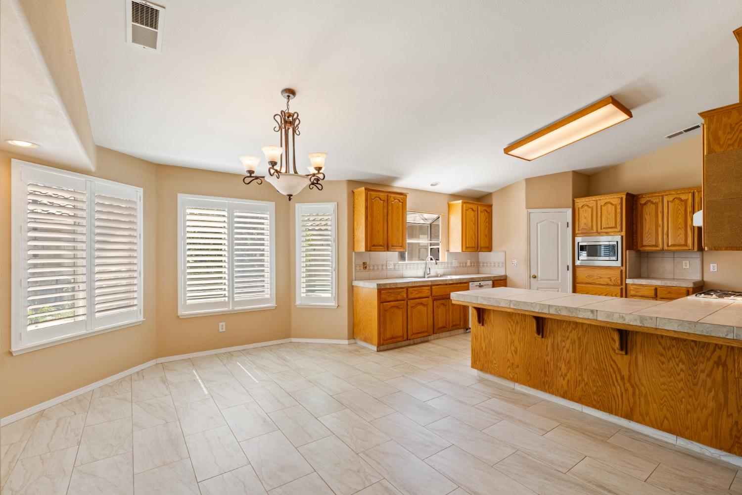 43 East Loop Madera, CA 93637 - Photo 14 of 49 a view of a kitchen with kitchen island a sink wooden floor and a large window