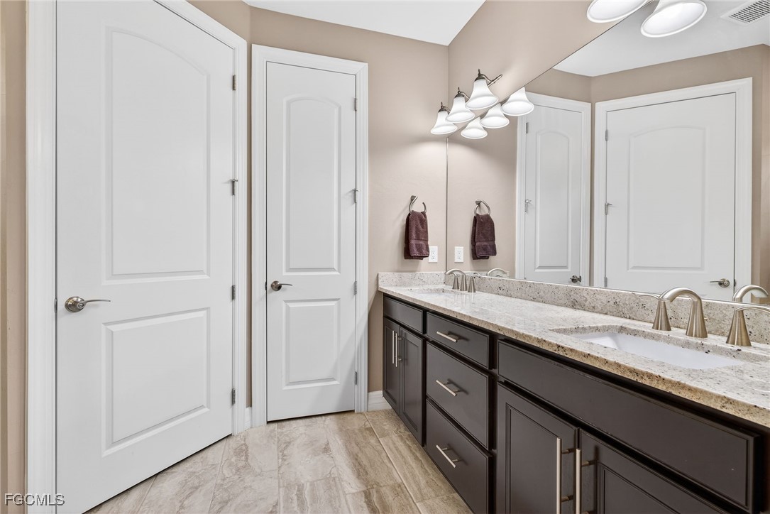 11800 Benchley Court Fort Myers, FL 33913 - Photo 18 of 50 a bathroom with a double vanity sink and mirror