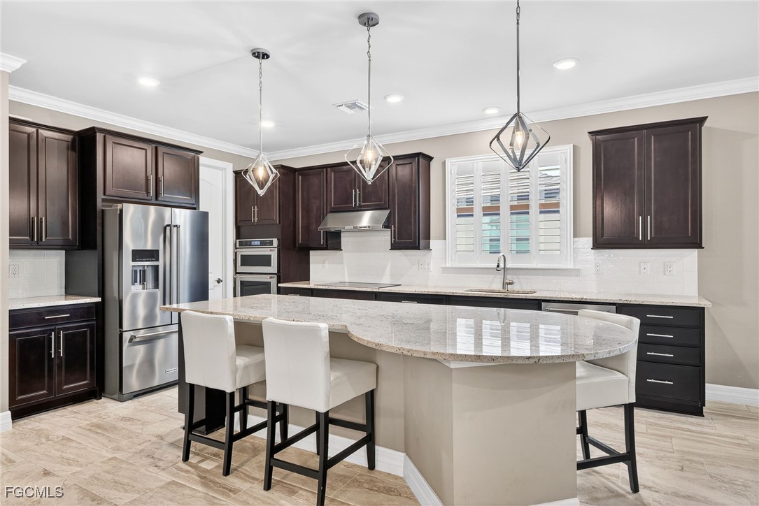 11800 Benchley Court Fort Myers, FL 33913 - Photo 6 of 50 a kitchen with kitchen island granite countertop a table chairs refrigerator and microwave