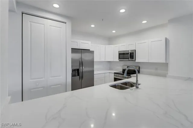 a kitchen with granite countertop a refrigerator and a sink