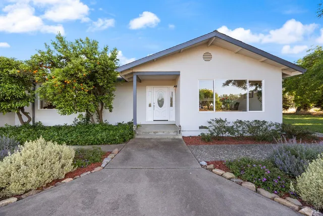 a front view of a house with a yard and potted plants