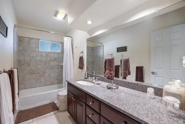 a bathroom with a granite countertop bathtub sink and mirror