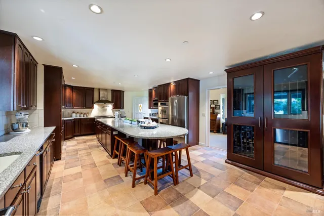 a kitchen with stainless steel appliances kitchen island granite countertop a table chairs and a refrigerator
