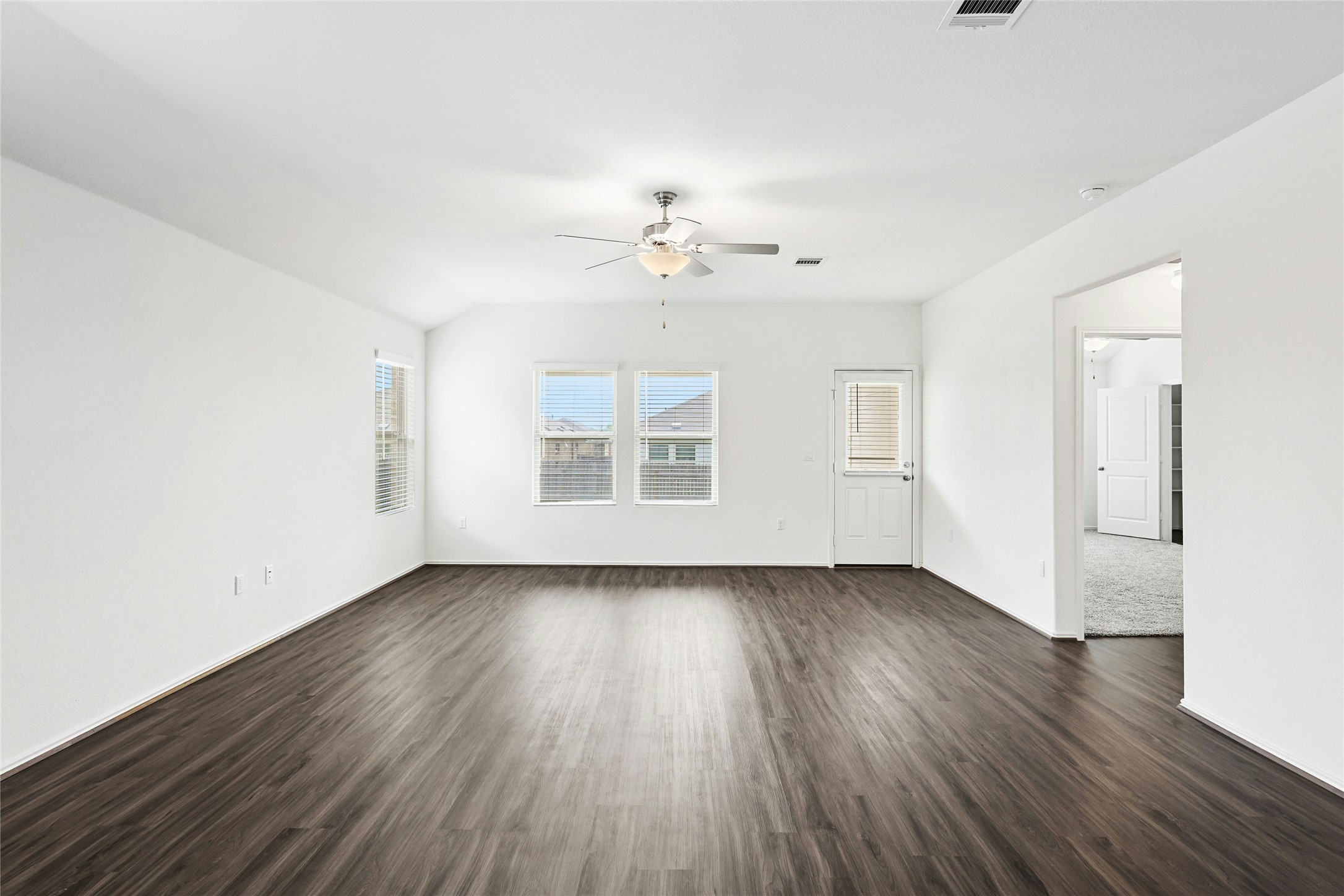 11813 Roscommon Trail Austin, TX 78754 - Photo 12 of 28 an empty room with wooden floor chandelier fan and windows