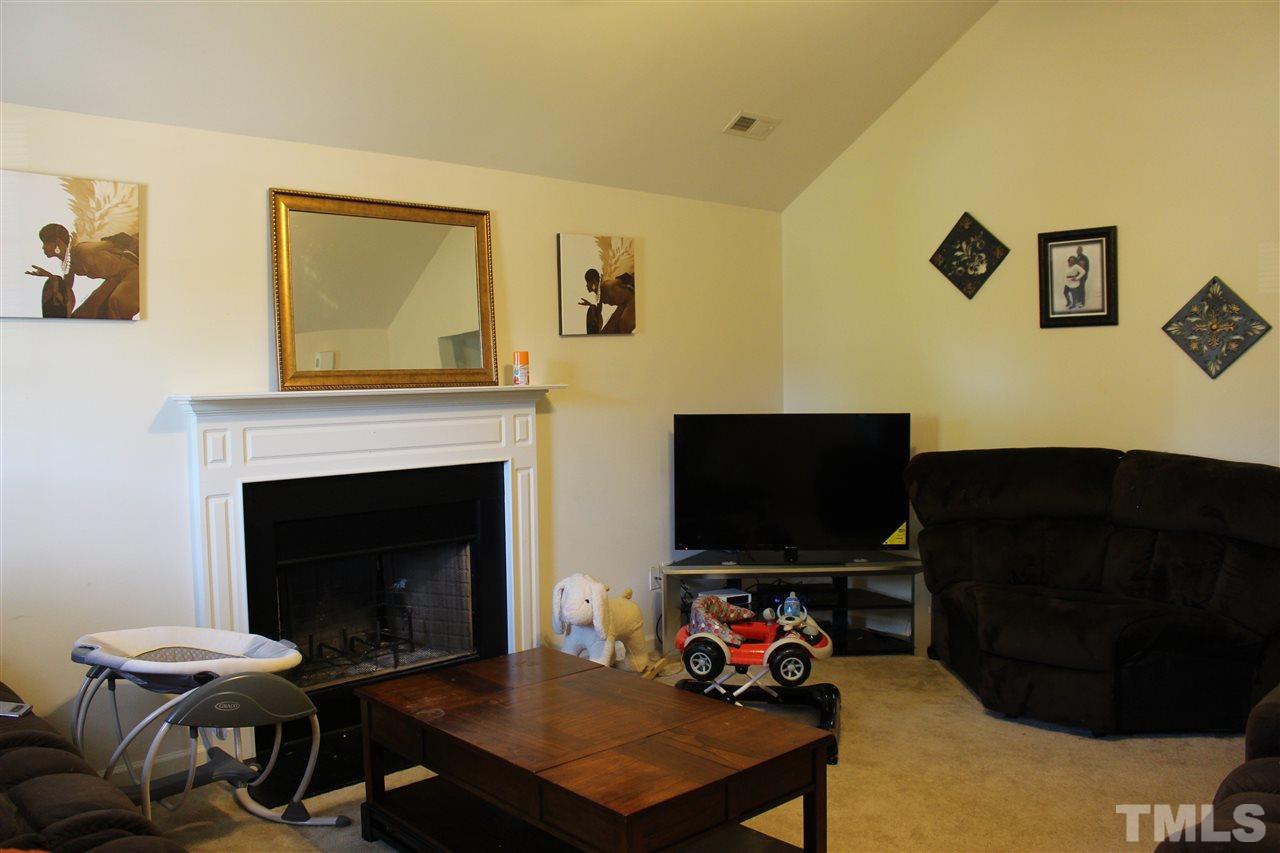 1432 Ricochet Drive Raleigh, NC 27610 - Photo 7 of 23 a living room with furniture a flat screen tv and a fireplace