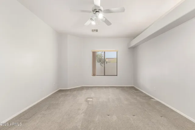 an empty room with chandelier fan and windows