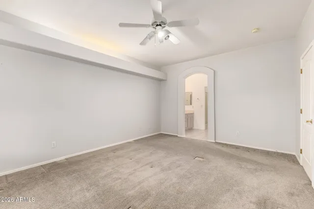 an empty room with a chandelier fan and windows