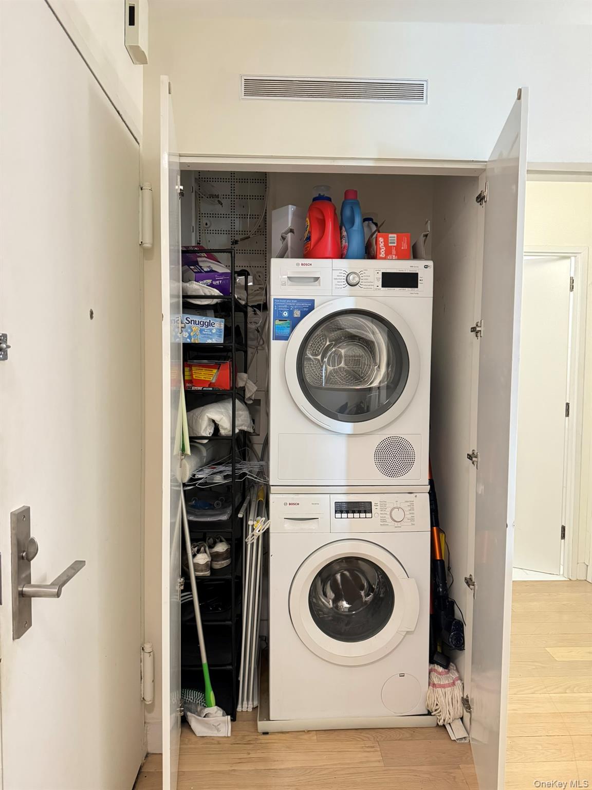 301 West 53rd Street, Unit 9K Manhattan, NY 10019 - Photo 14 of 22 Washroom with light wood-style floors and stacked washer and clothes dryer