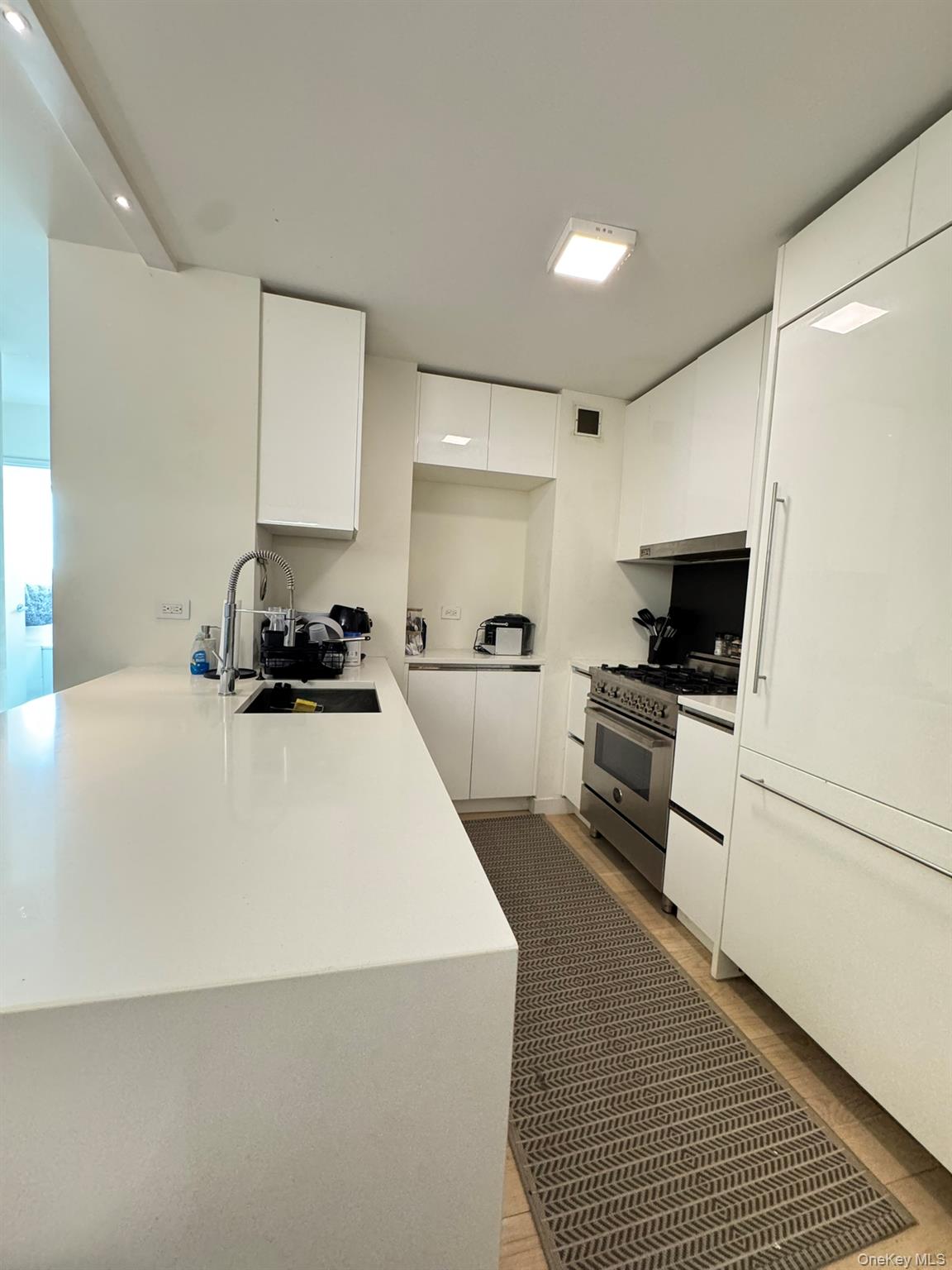 301 West 53rd Street, Unit 9K Manhattan, NY 10019 - Photo 2 of 22 Kitchen with white cabinets, stainless steel stove, light stone countertops, modern cabinets, and a peninsula