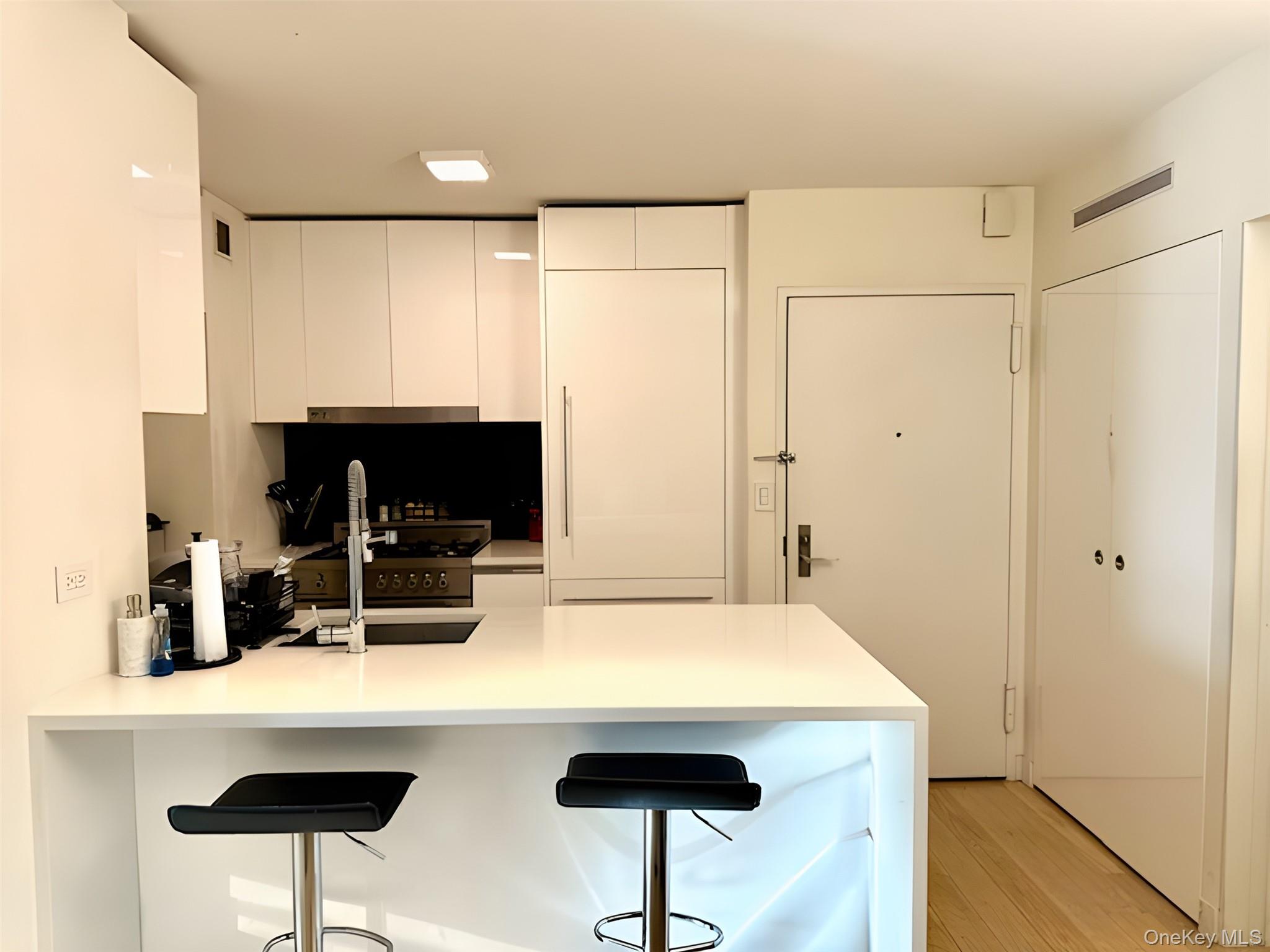 301 West 53rd Street, Unit 9K Manhattan, NY 10019 - Photo 3 of 22 Kitchen with a peninsula, modern cabinets, a kitchen breakfast bar, white cabinetry, and light stone countertops