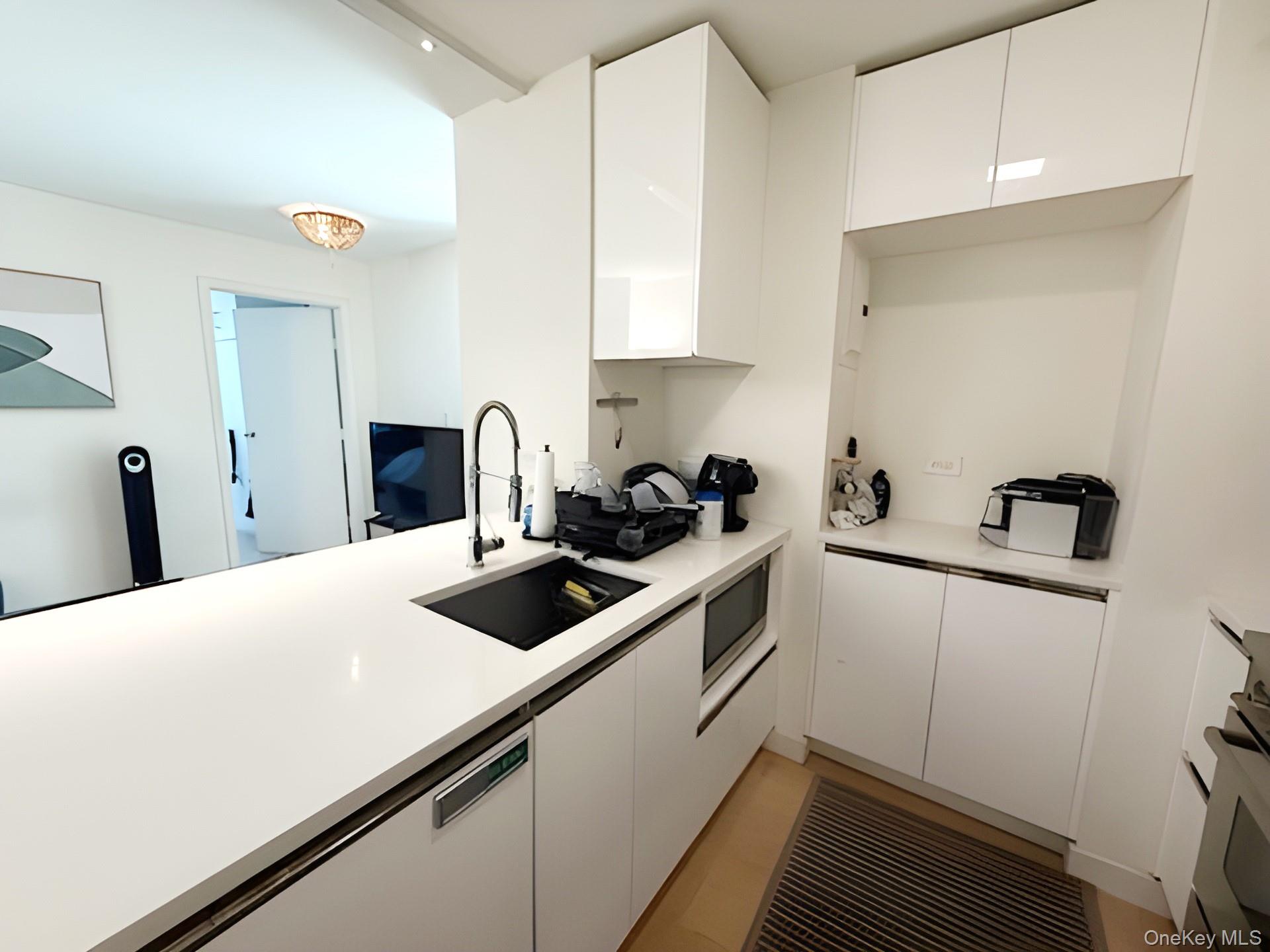301 West 53rd Street, Unit 9K Manhattan, NY 10019 - Photo 5 of 22 Kitchen featuring modern cabinets, white cabinetry, white range, and stainless steel microwave