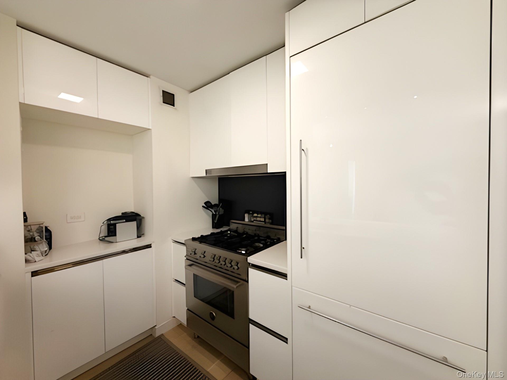 301 West 53rd Street, Unit 9K Manhattan, NY 10019 - Photo 7 of 22 Kitchen with white cabinets, stainless steel stove, light countertops, modern cabinets, and light tile patterned floors