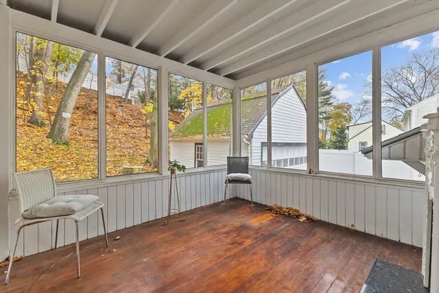 a view of an empty room with wooden floor fireplace and a window